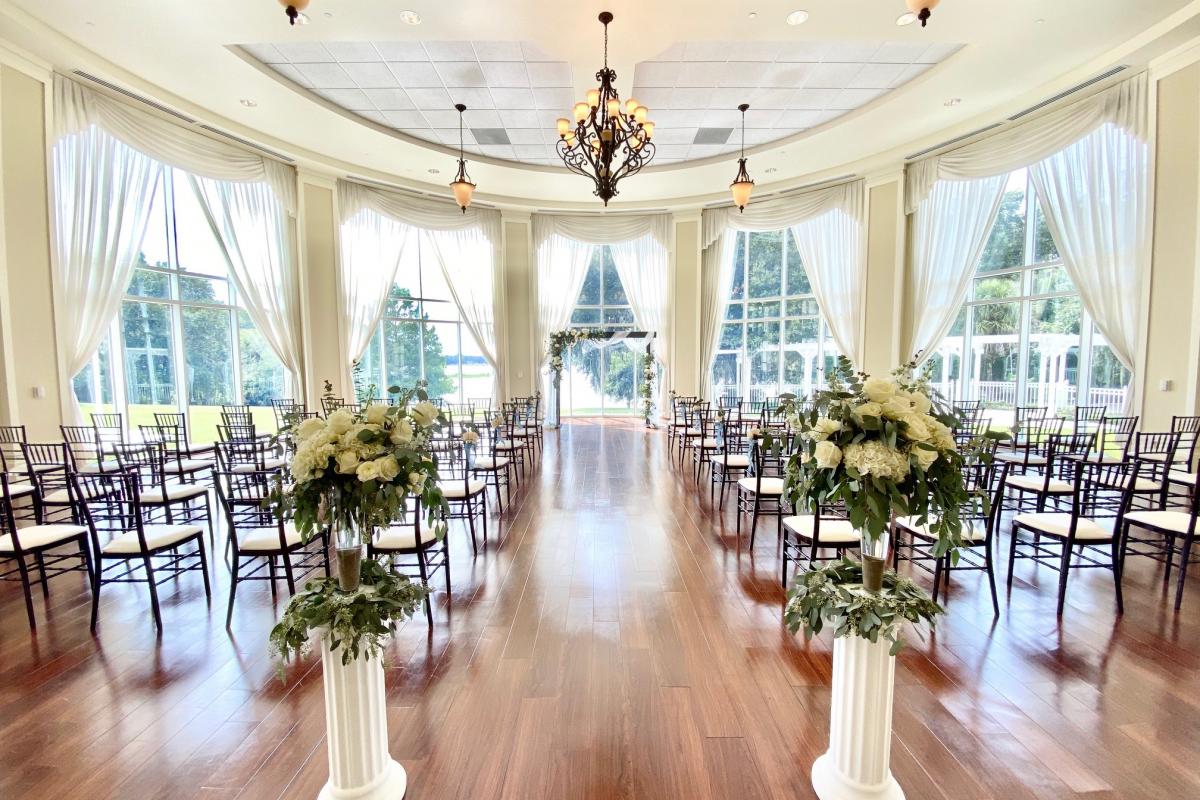 View from the back of an indoor wedding set up in front of large window