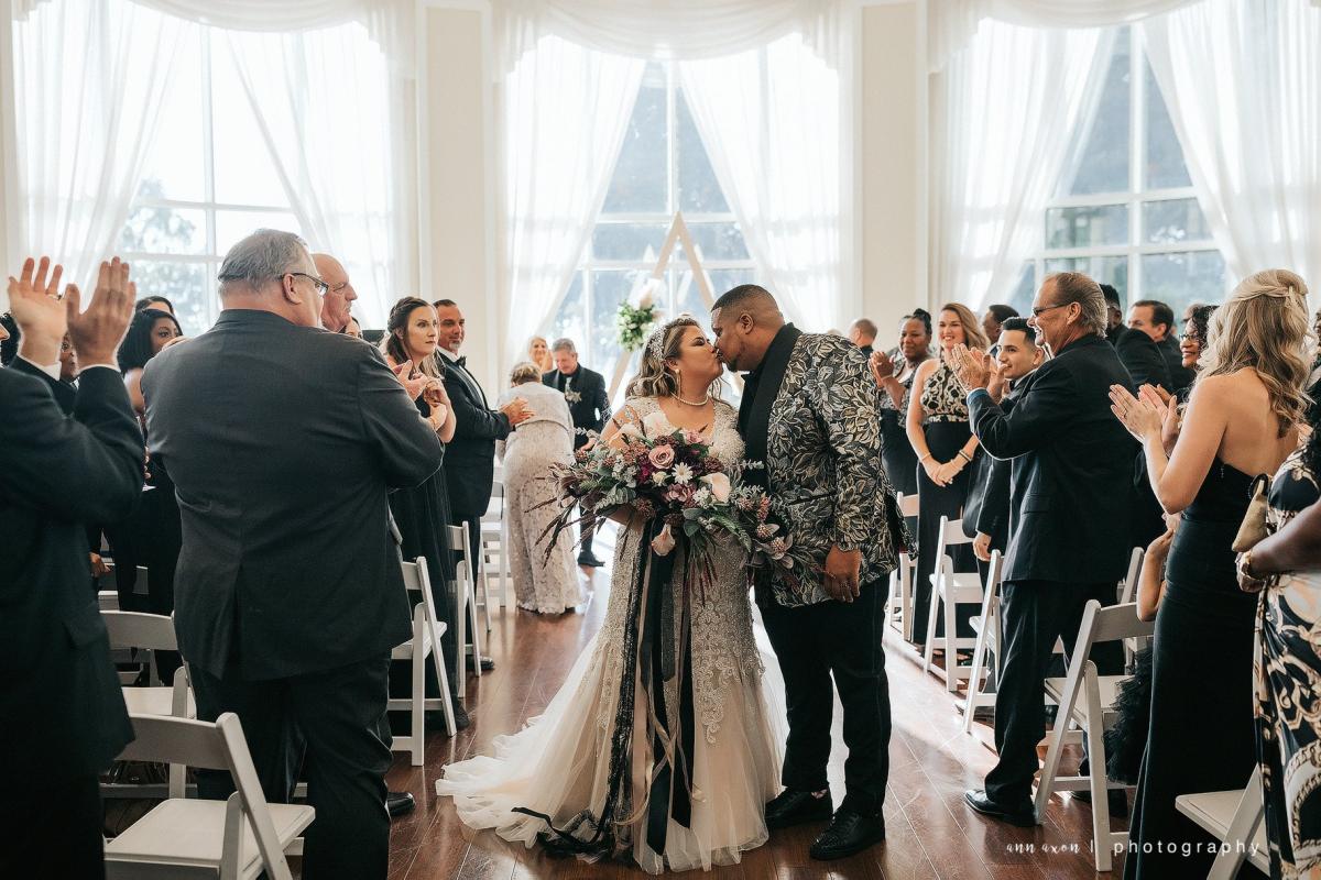 Bride and groom kiss at the end of the aisle