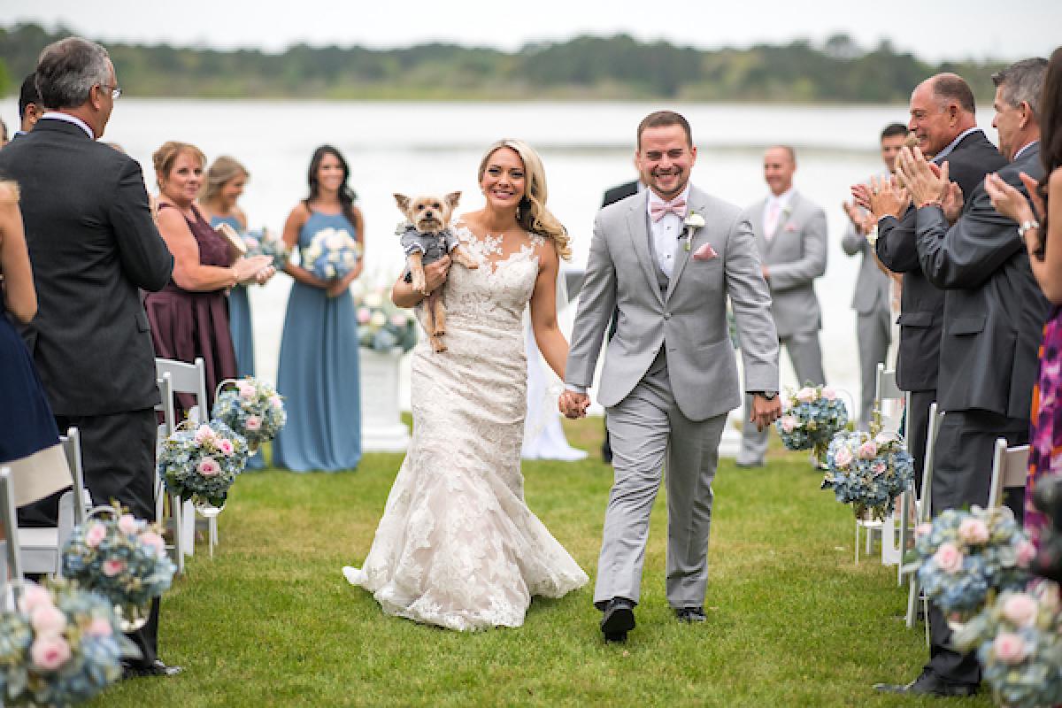 Bride and groom walking down the aisle with a dog