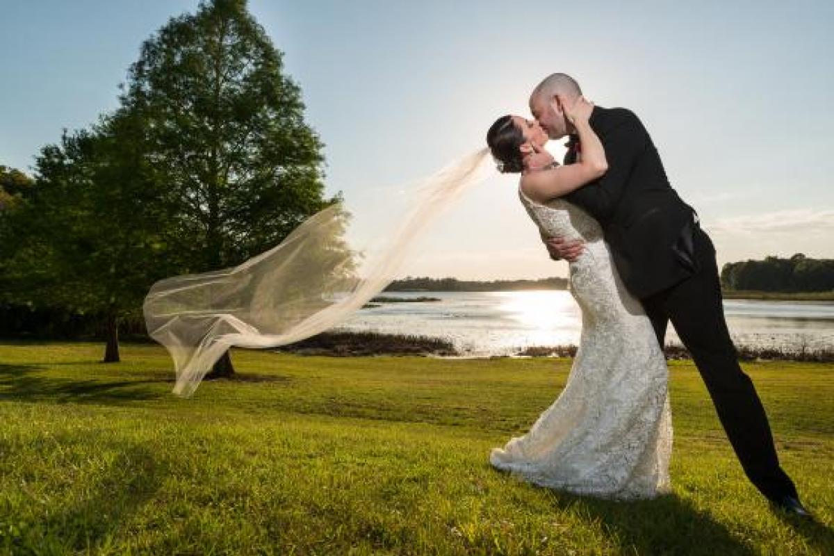 Bride and groom kissing in front of lake